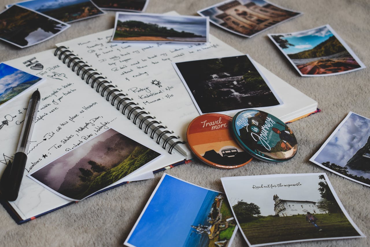 Travel diary surrounded by printed photos and a pen, capturing memories creatively.